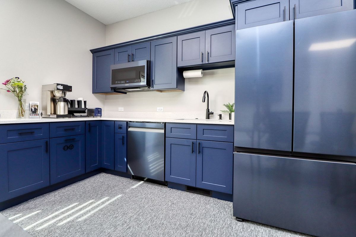 Blue kitchen with matching cabinets, stainless steel appliances, and speckled flooring