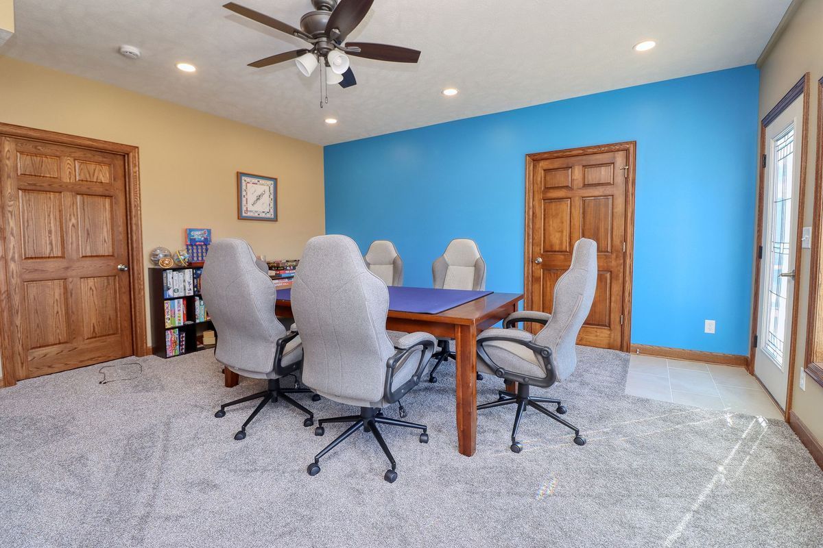 Spacious room with blue walls, carpet, wooden doors, and a dining table with six upholstered chairs.