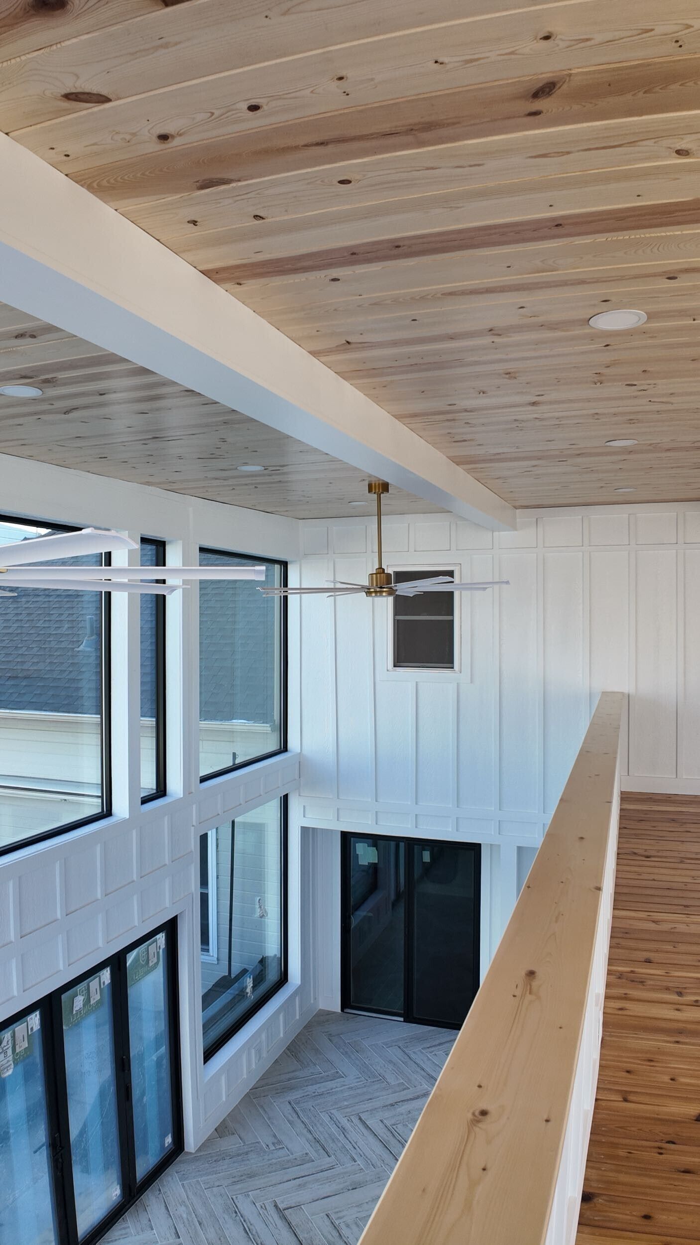 Modern atrium with wood ceiling, large windows, white walls, and a hanging pendant light