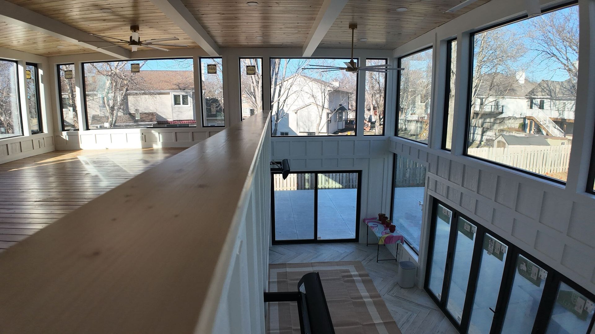Interior balcony walkway overlooking a bright modern atrium with large windows and glass doors