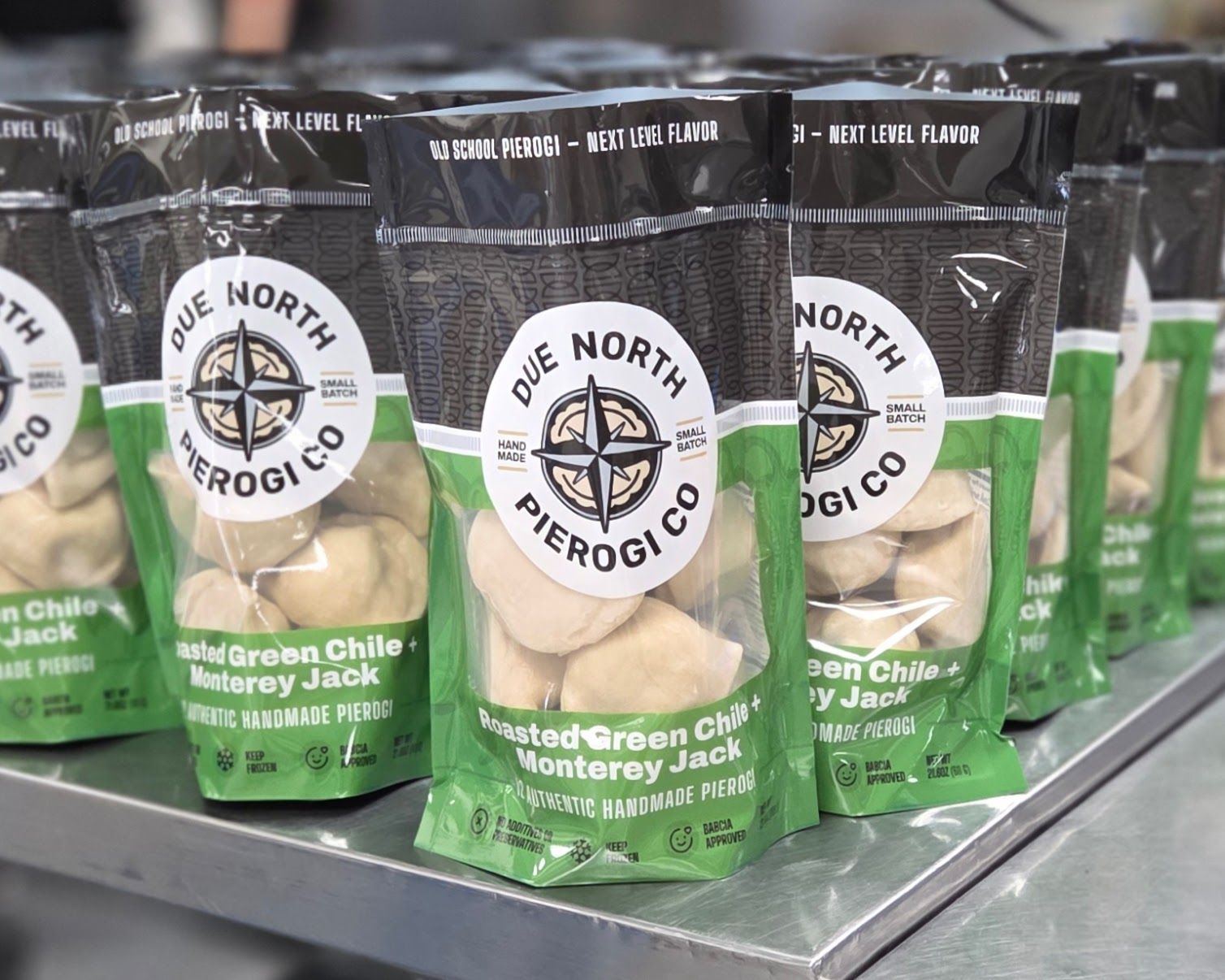 Packages of Due North pierogi in black and green bags on a store shelf