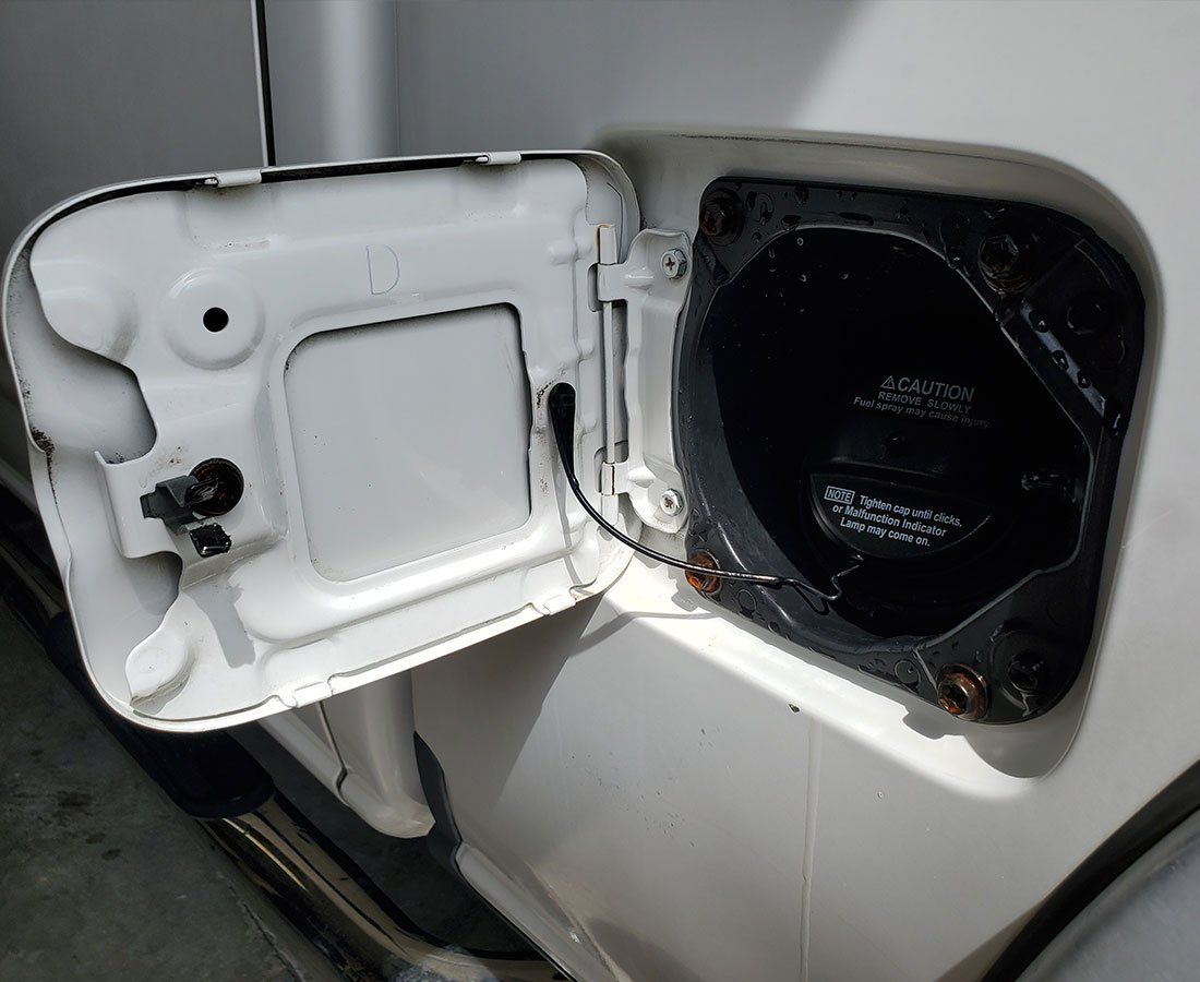 Open white car gas tank door; black fuel filler neck visible.