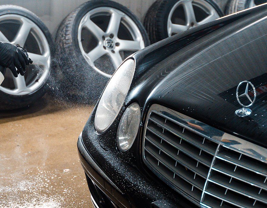 Black car being sprayed with water; spare tires in the background.