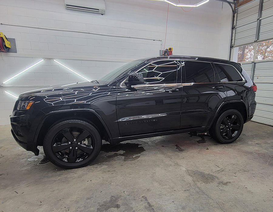 Dark gray Jeep Grand Cherokee SUV parked in a garage with black rims.