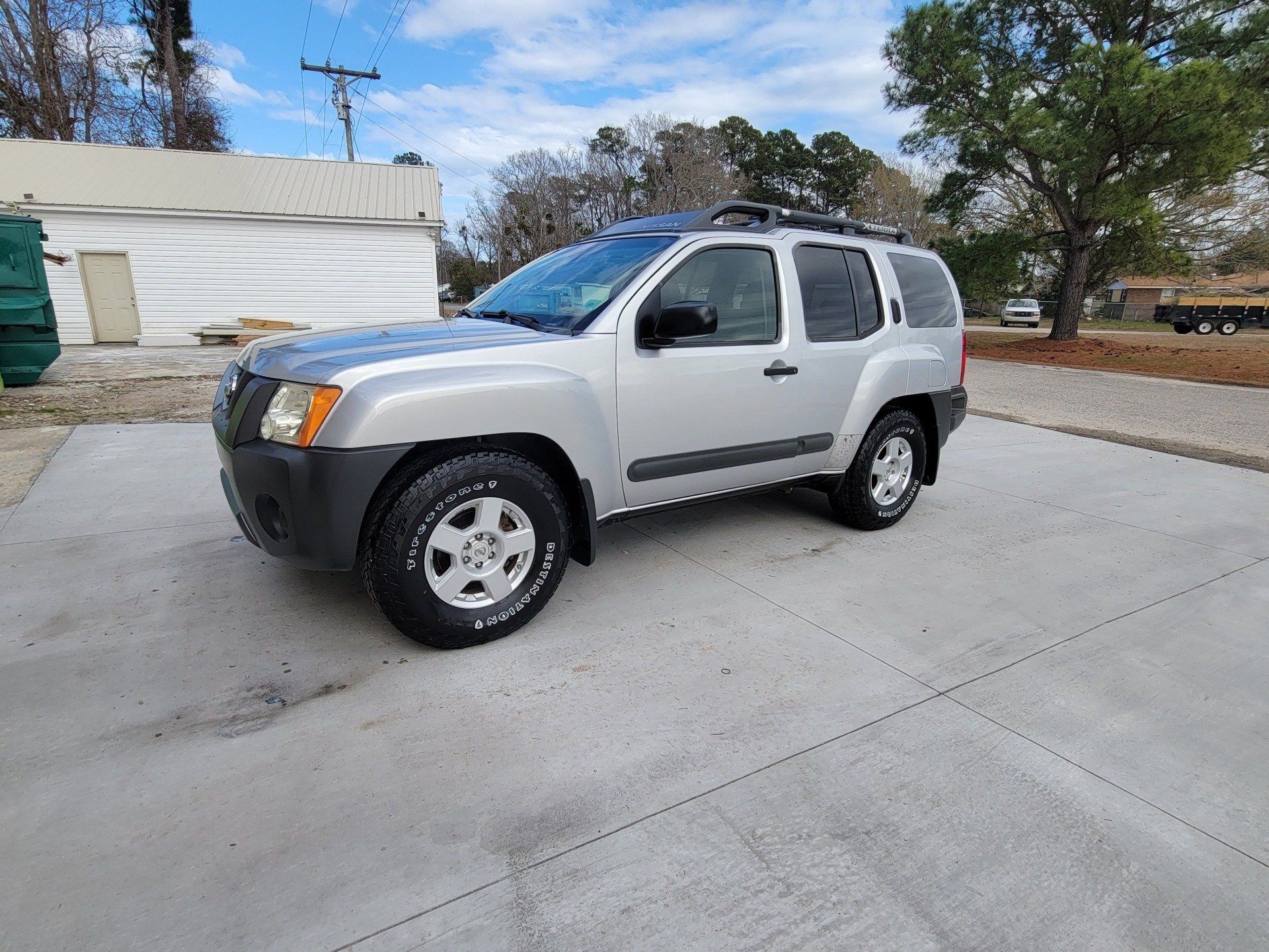 Silver Nissan Xterra SUV parked on a concrete surface.