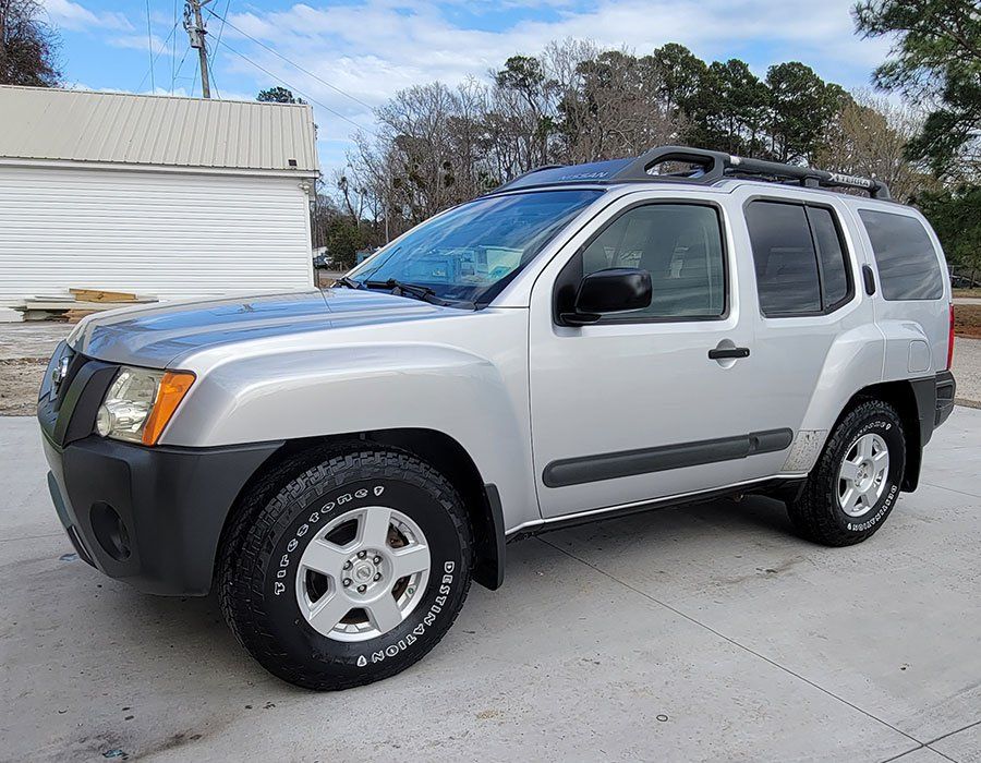 Silver Nissan Xterra SUV parked outdoors on a sunny day.