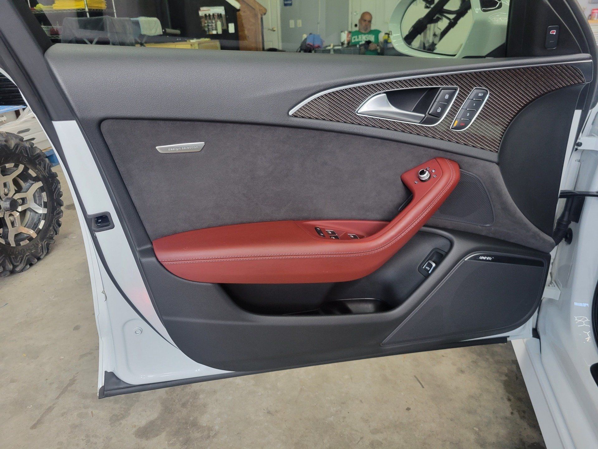 White car door with red leather armrest, black panel, and gray suede.