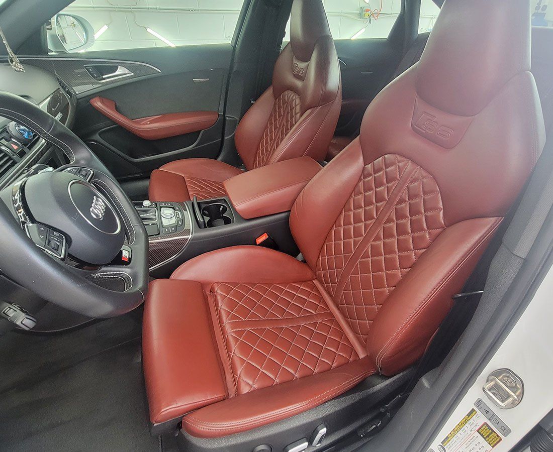 Red leather car interior with quilted seats, black steering wheel.