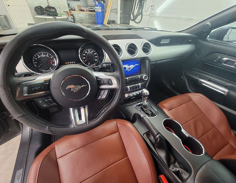 Interior view of a Mustang car with brown leather seats, a black steering wheel, and a center console.