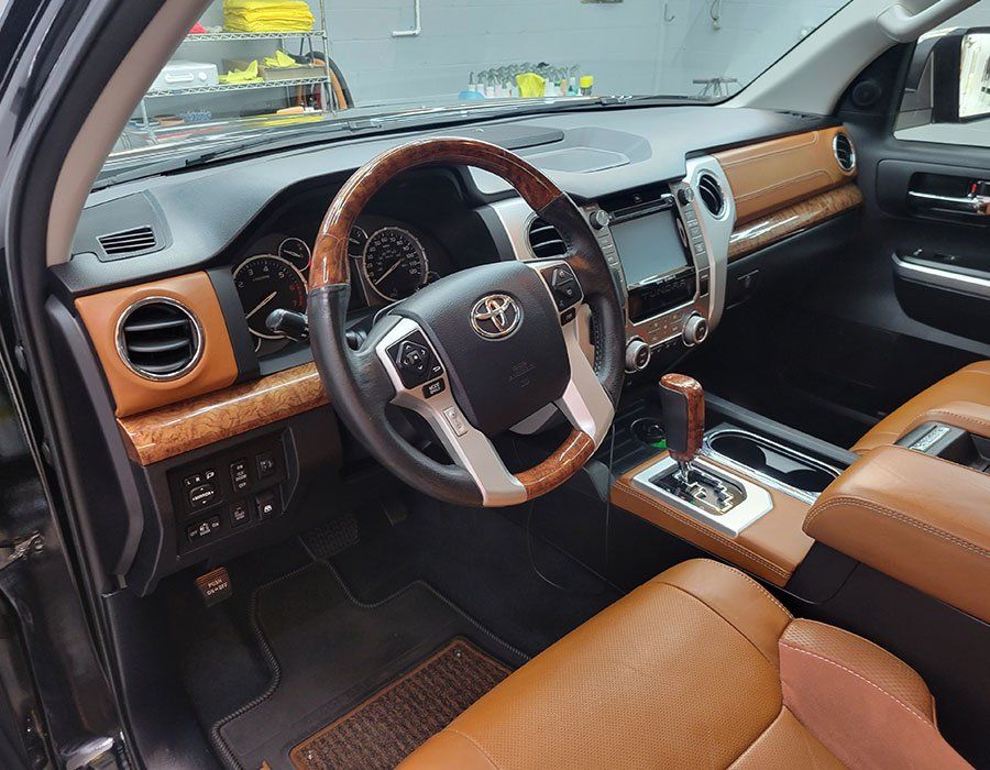 Interior of a Toyota Tundra truck with brown leather seats and wood accents.