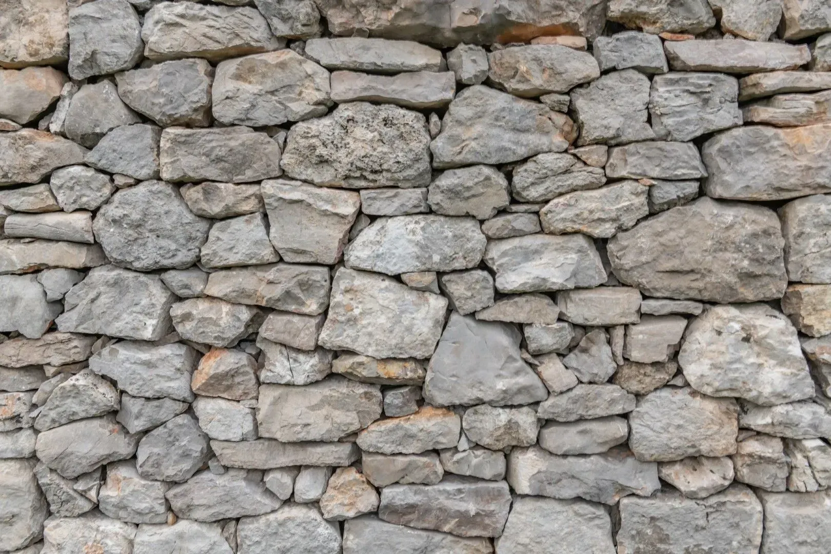 Close-up of a gray stone wall made of rough, irregular rocks.