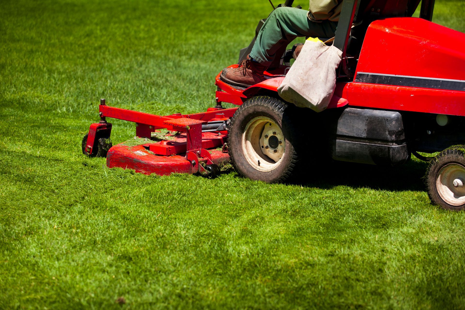 Red riding lawnmower mowing a vibrant green lawn on a sunny day.