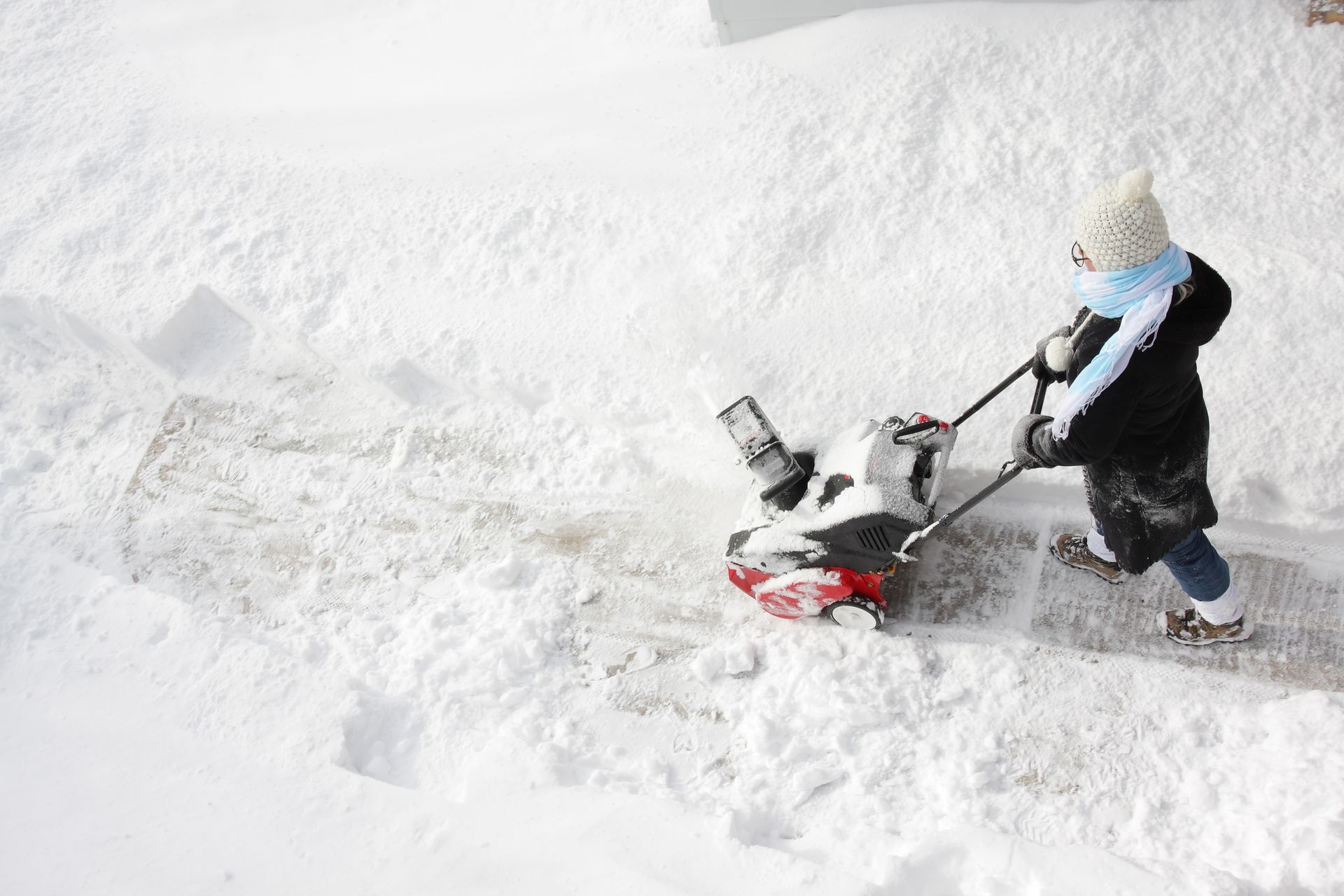 Person using a snowblower to clear a snowy walkway.