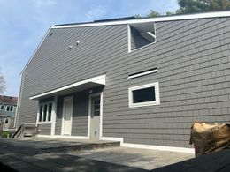 A gray brick house with a white trim is being remodeled