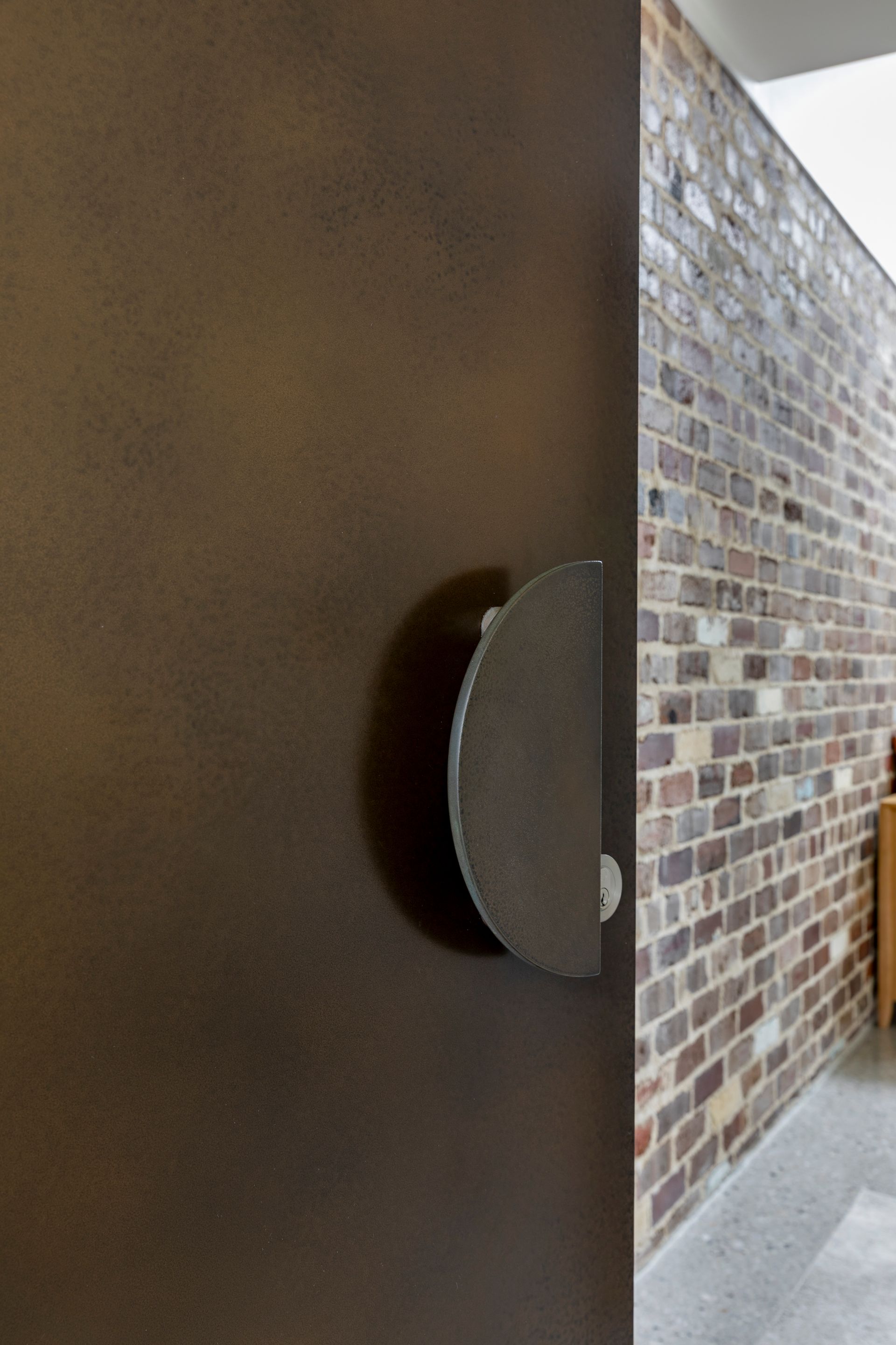 Open door showing a brick-walled entryway and dark interior wall handle.