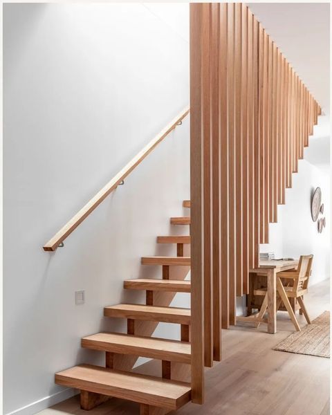 Wooden staircase with wood slat railing, light wood treads, and a light-colored wall.