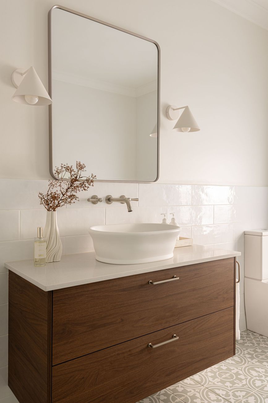 Bathroom vanity with a wooden cabinet, a white vessel sink, and a large mirror.