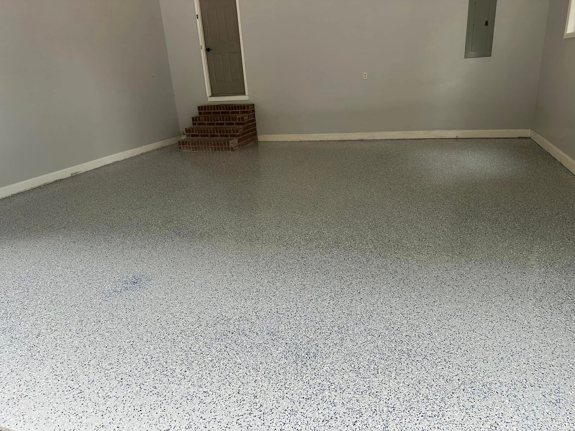 Empty gray room with speckled floor and white walls