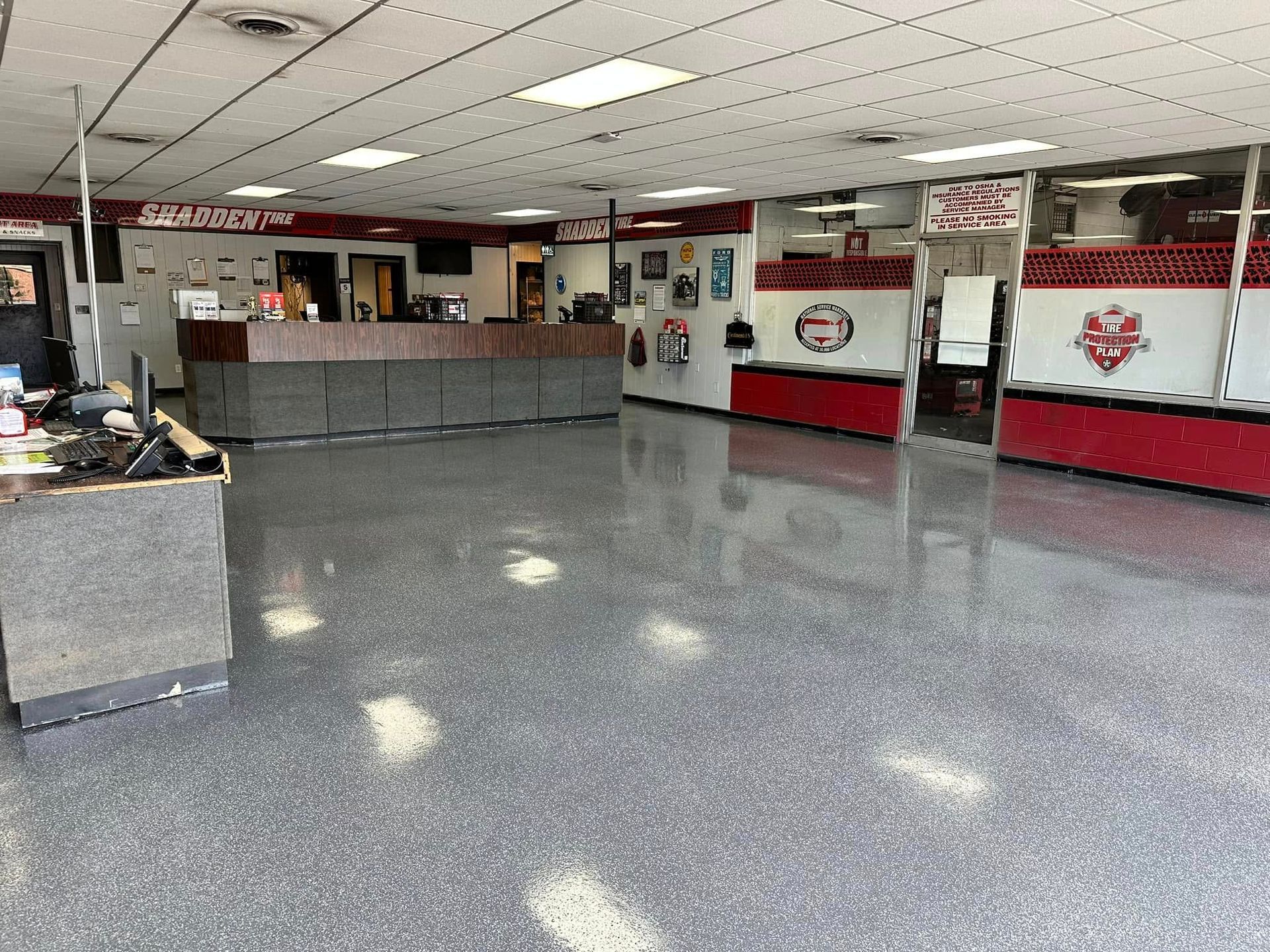 Empty lobby with gray floor, red-and-white walls, and a front counter in a bright indoor space