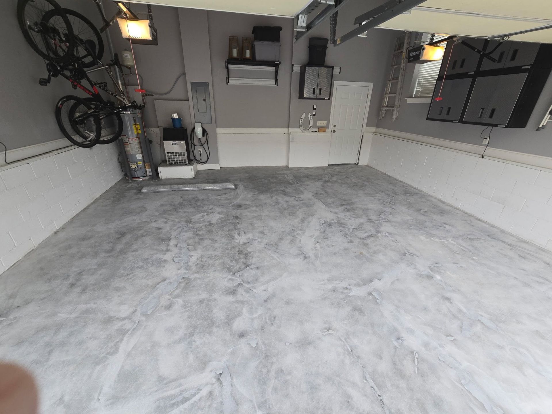 Concrete garage floor with wall-mounted equipment, bicycle, and storage cabinets.