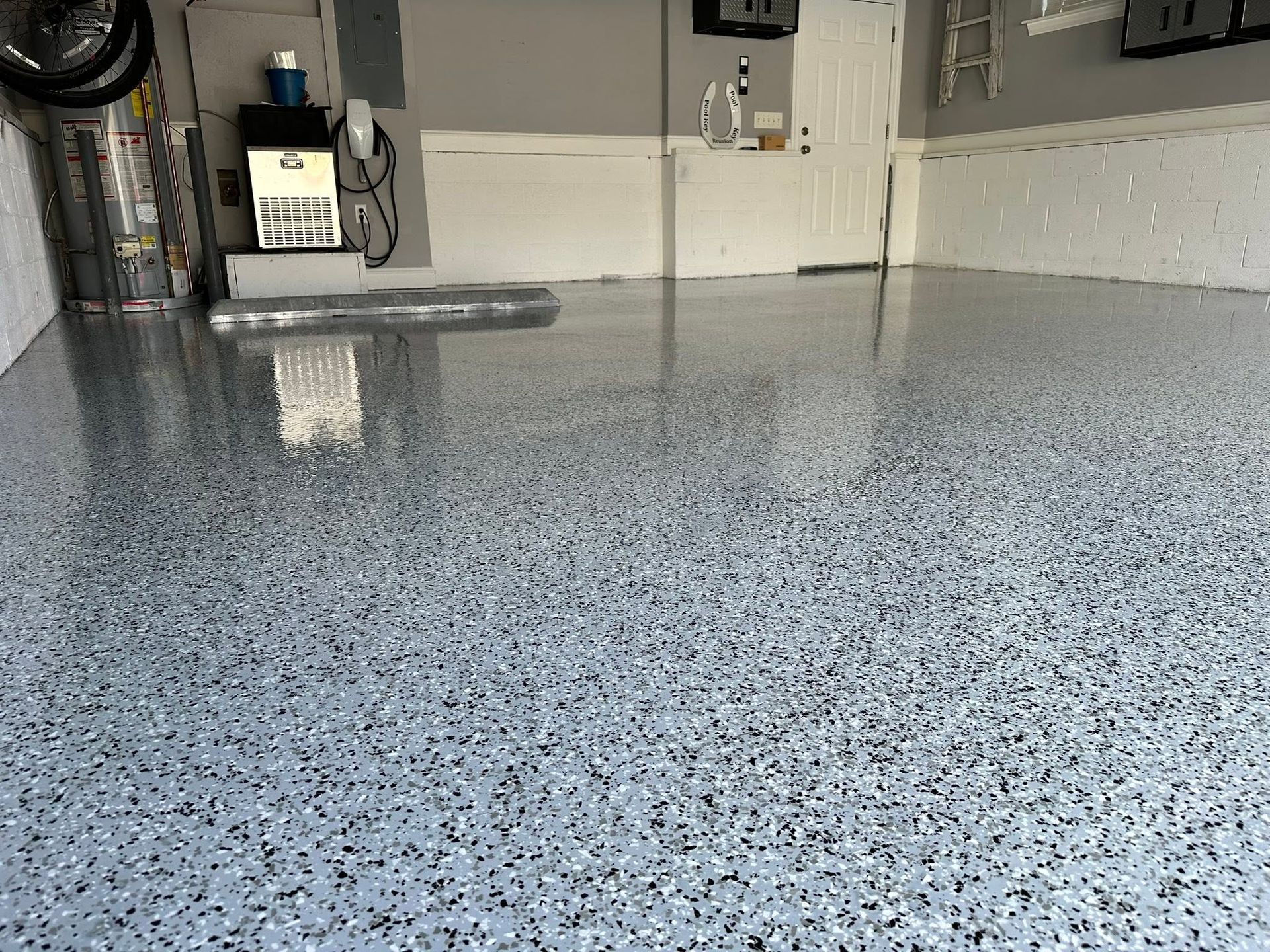 Garage with a glossy speckled epoxy floor and utility equipment in the background
