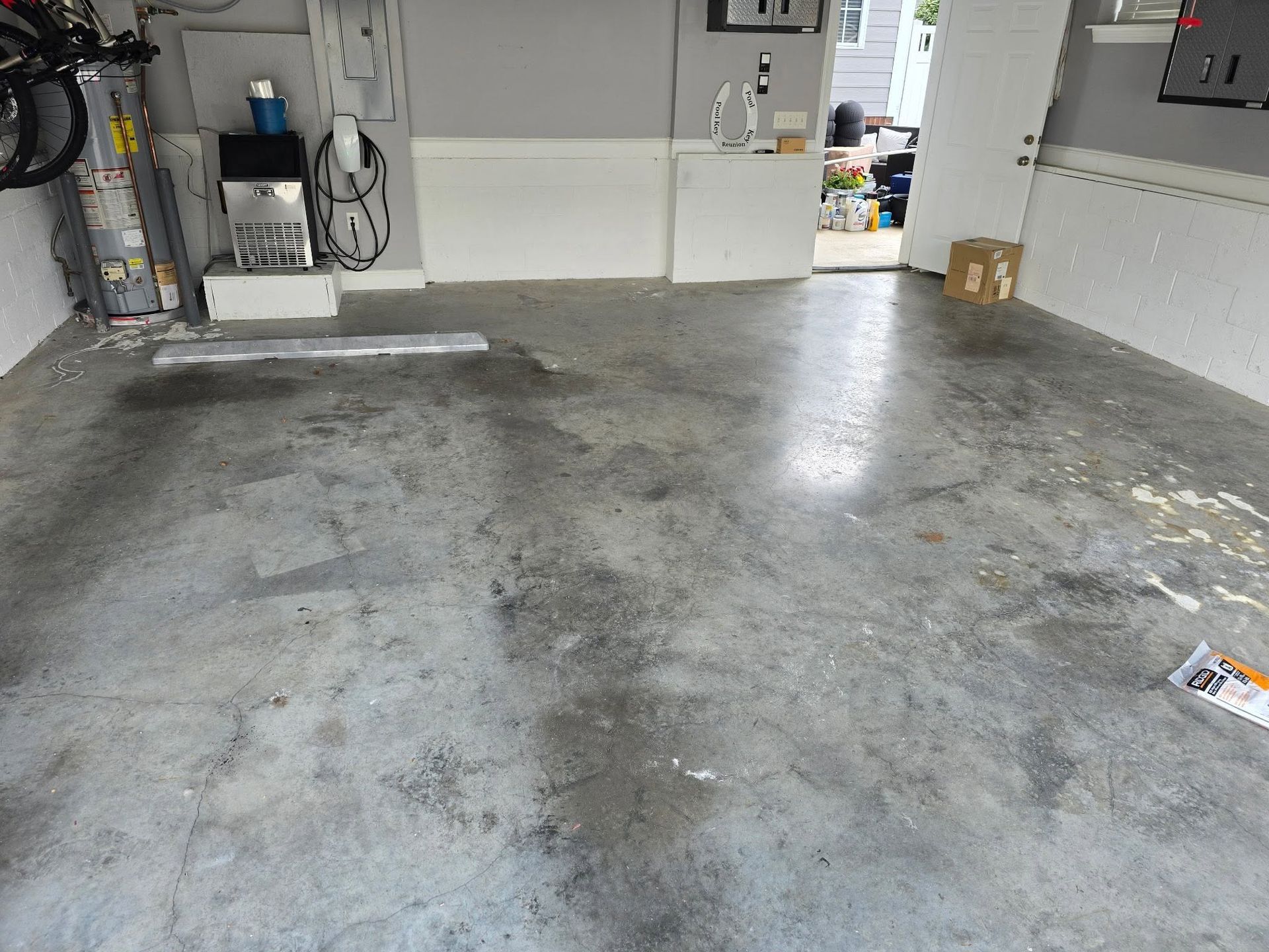 Empty garage with a stained concrete floor and white walls, viewed toward the back wall.