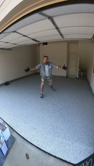 Man standing with arms outstretched in a garage with a partially open door
