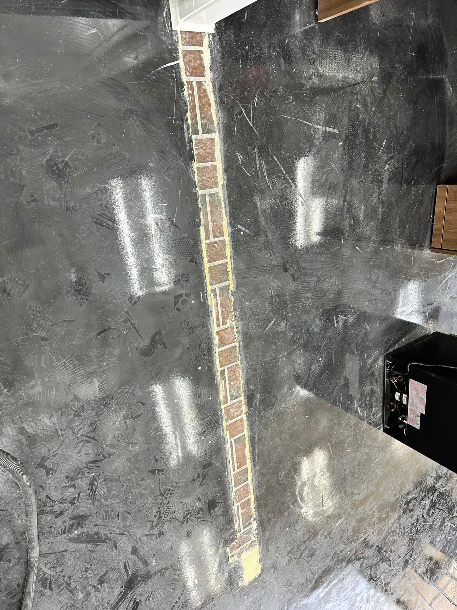 Damaged concrete floor with a narrow brick strip running vertically through the center