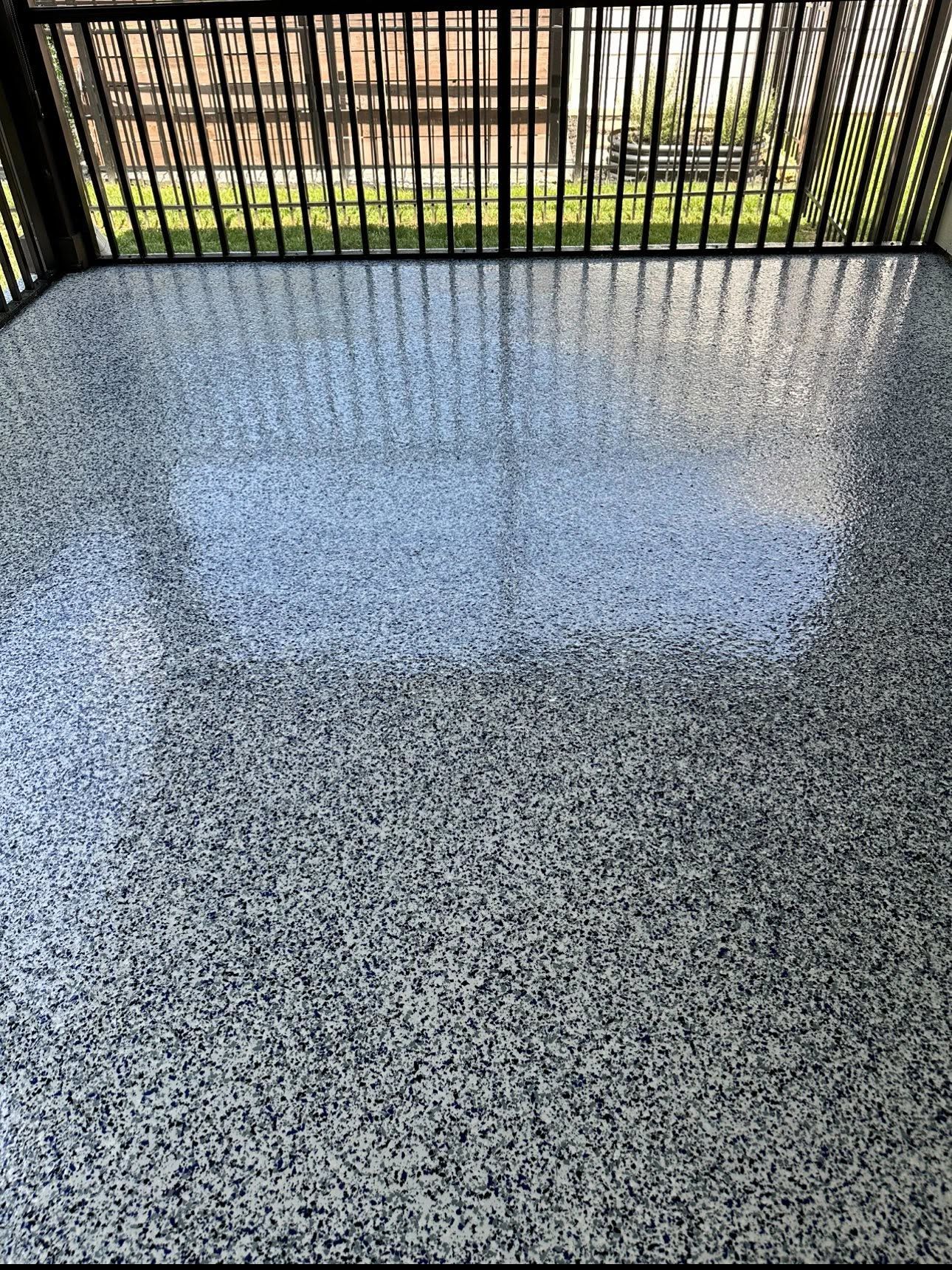 Speckled gray balcony floor with black metal railing and sunlight reflection