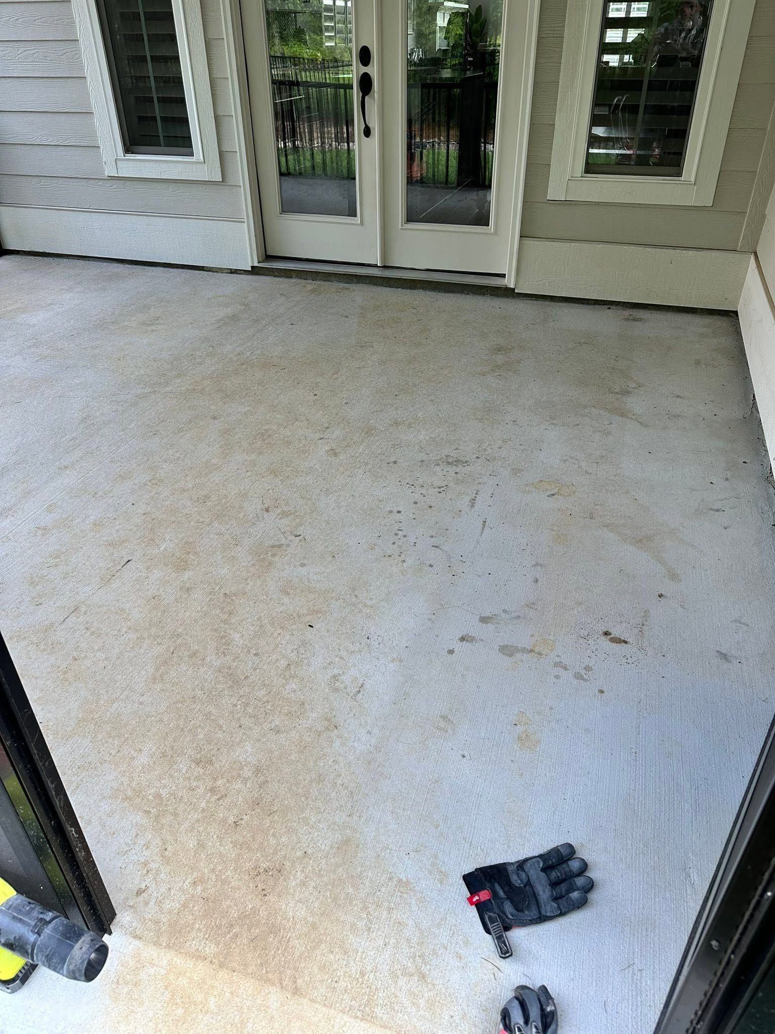 Light gray porch floor with double glass doors and a small black-and-red glove near the bottom right.