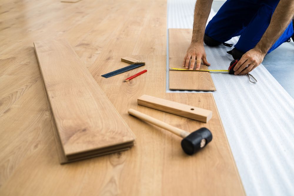 A man is measuring a piece of wood with a tape measure.