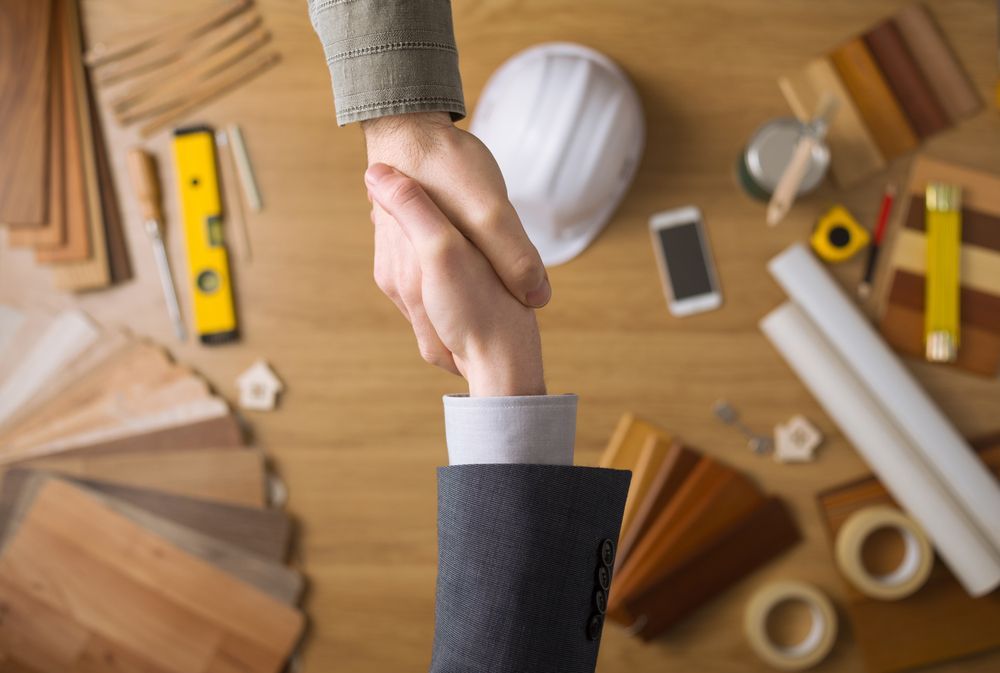 A man and a woman are shaking hands over a wooden table.