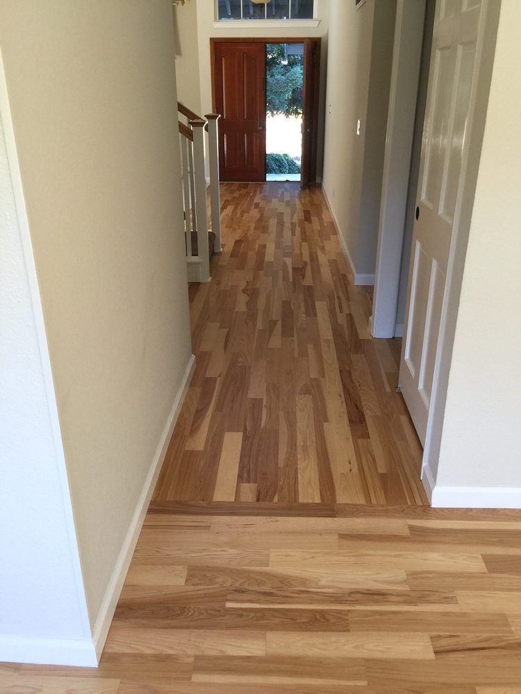 A hallway with hardwood floors and a staircase in a house.