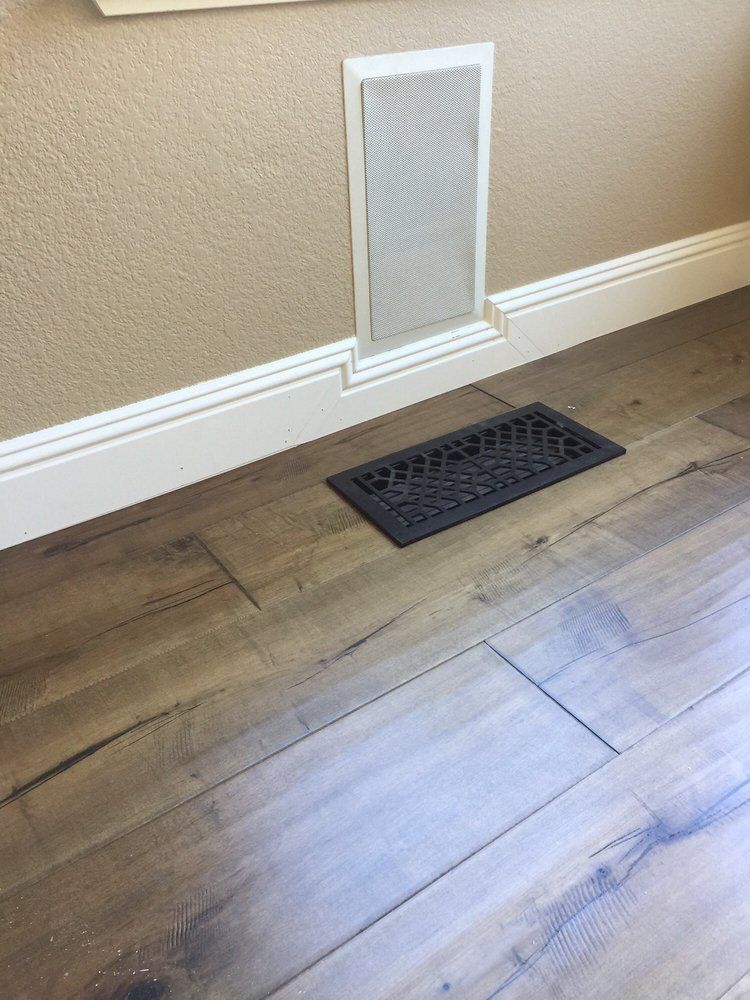 A room with hardwood floors and a vent on the floor.