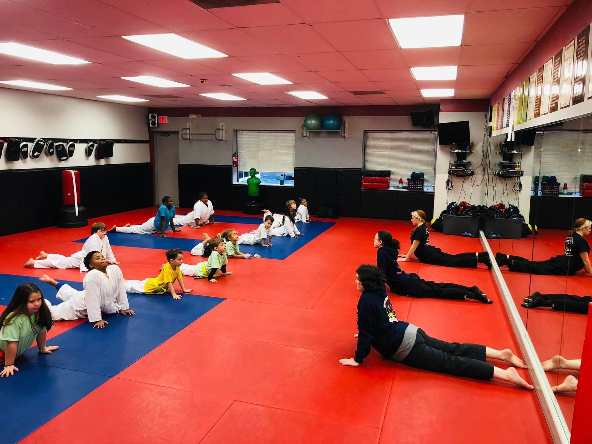 a group of kids are doing stretching exercises in a gym