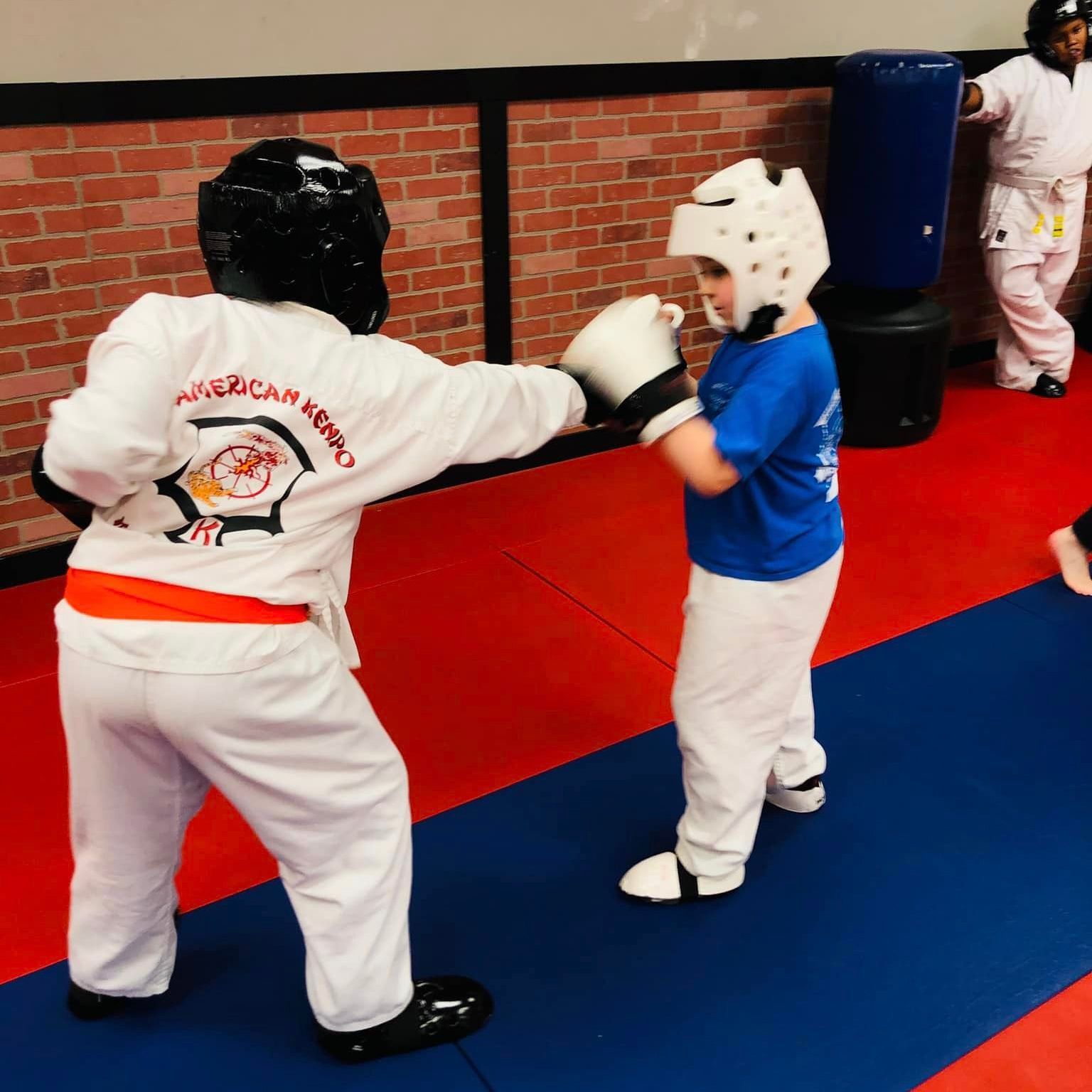 two young boys are practicing martial arts and one of them is wearing an american kendo uniform