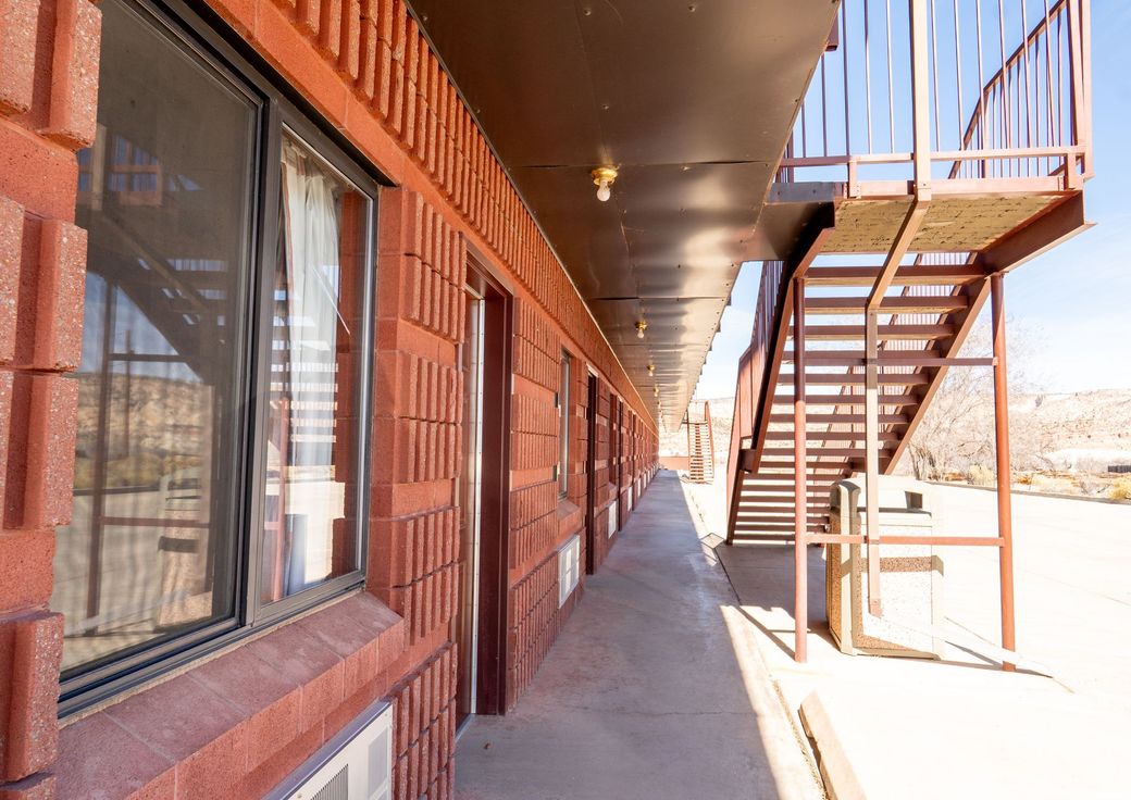 Exterior walkway beside brick apartments with windows and a metal staircase