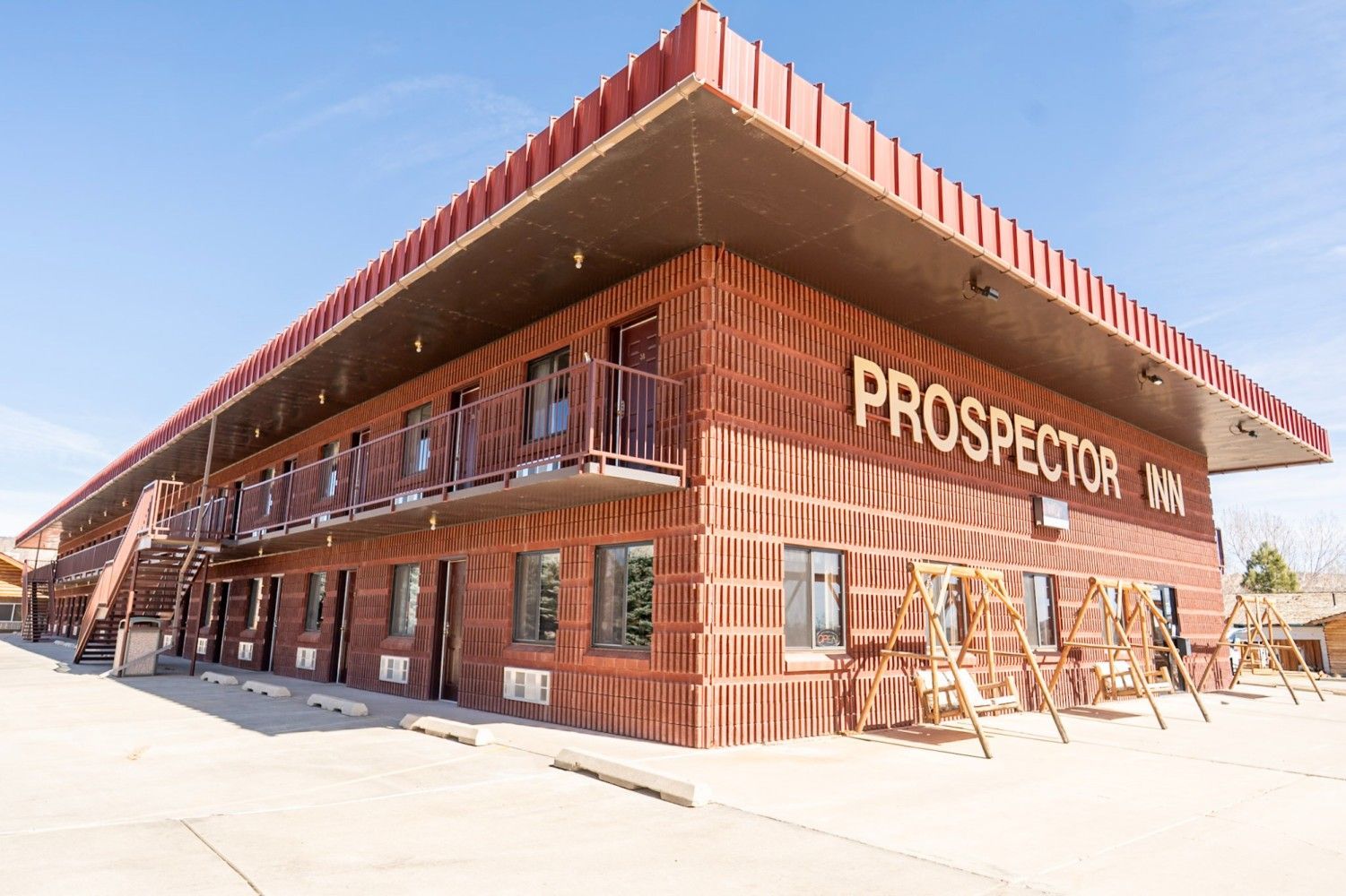 Brick building with a large overhang and “PROSPECTOR” sign on a sunny street corner