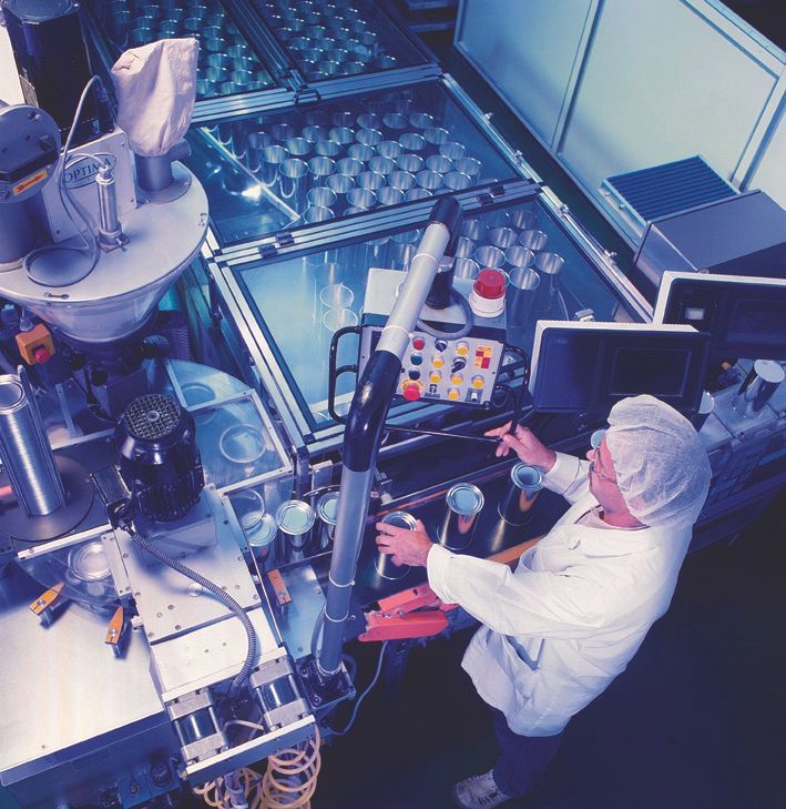 Una persona in camice da laboratorio aziona dei macchinari in una fabbrica;