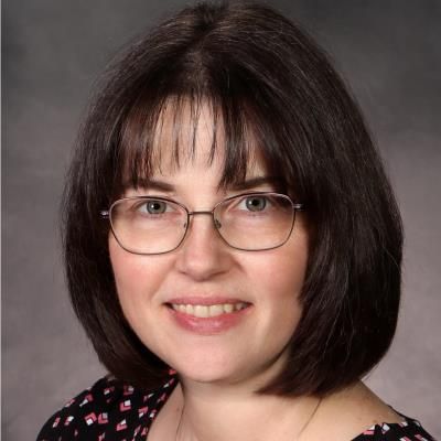A woman wearing glasses is smiling for the camera
