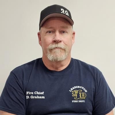 A man with a beard wearing a hat and a t-shirt that says fire chief d graham