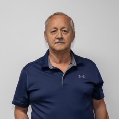 A man wearing a blue under armour shirt is standing in front of a white wall.