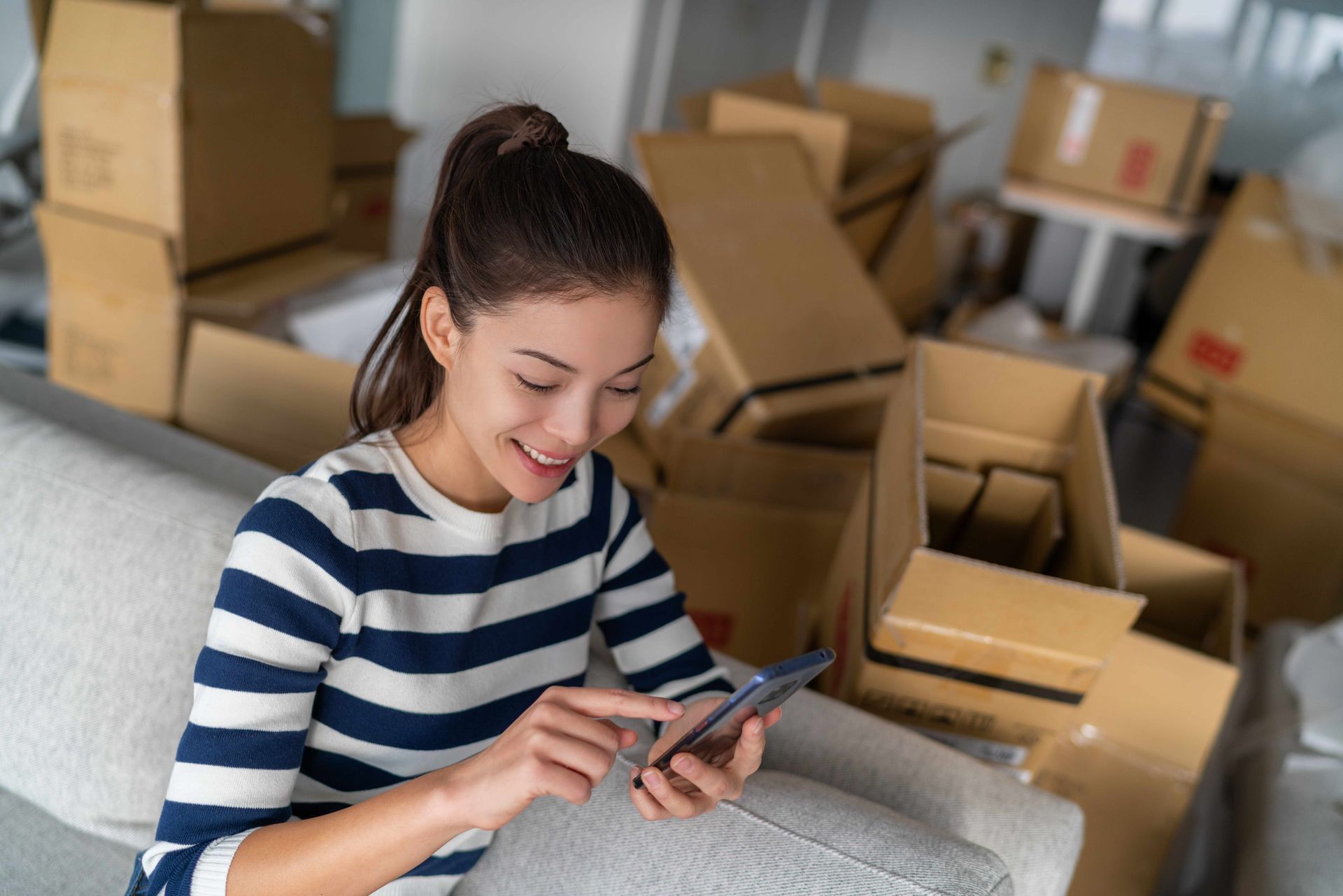 a woman is sitting on a couch using a cell phone .