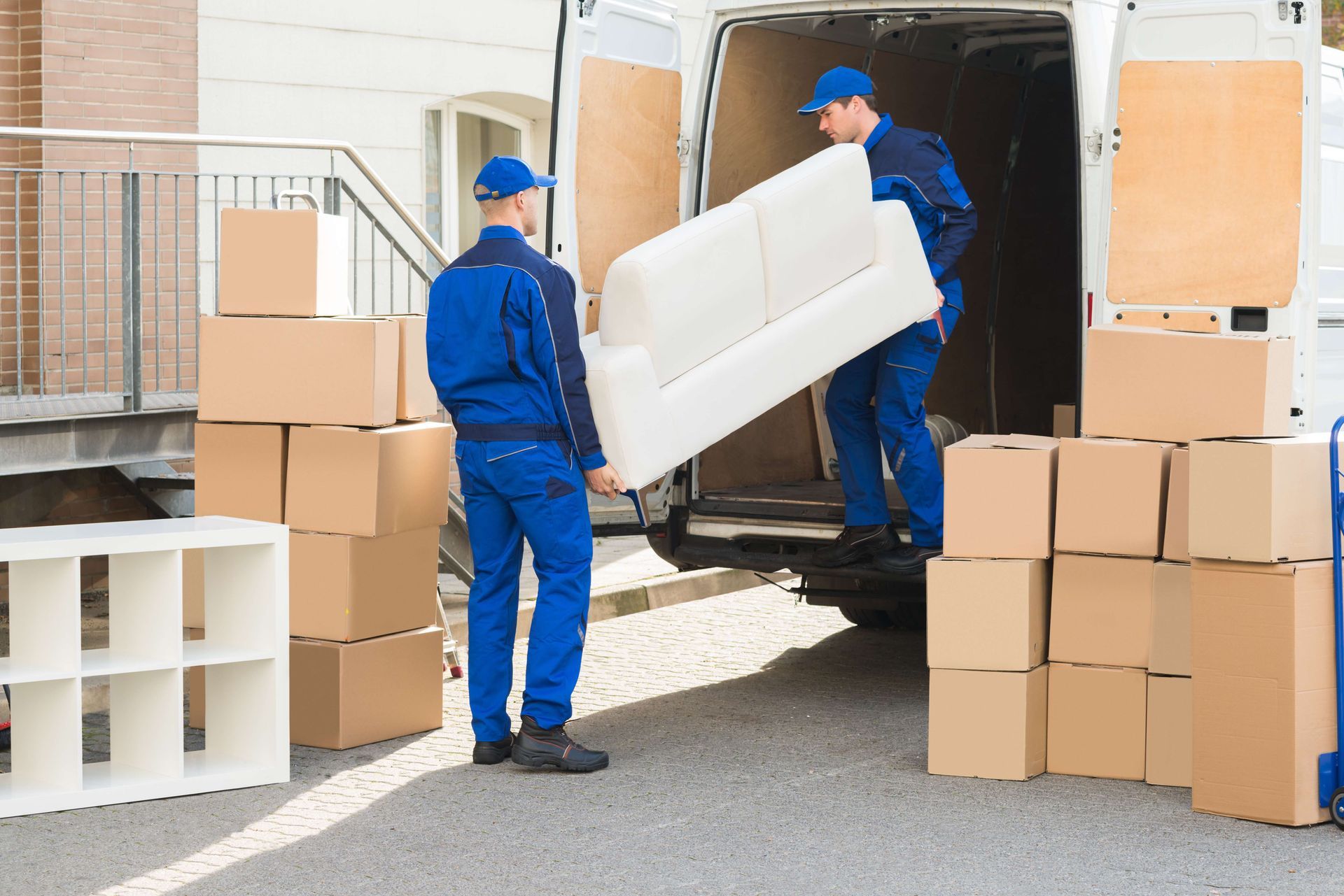 two movers are loading a couch into a van .