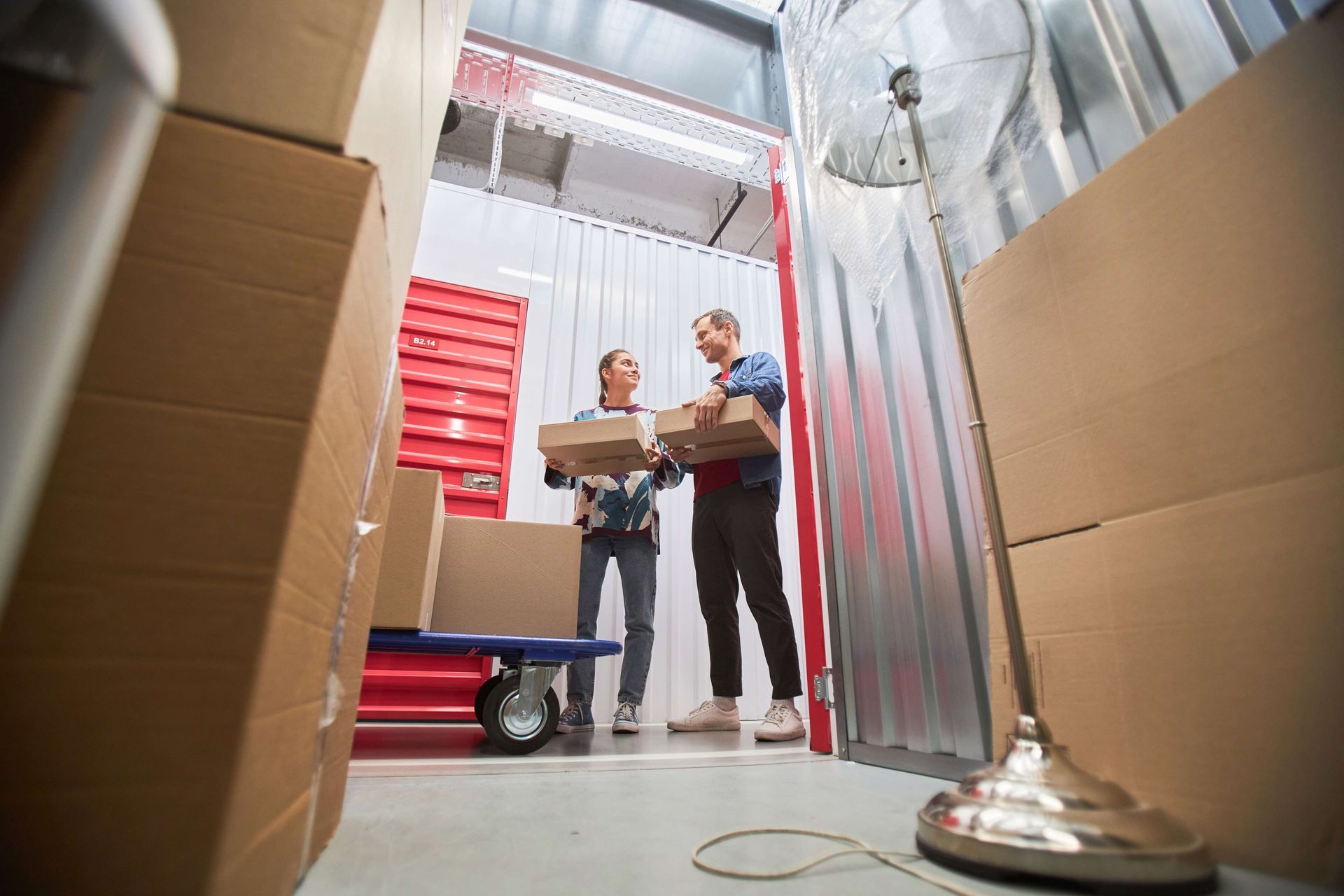 a man and a woman are holding boxes in a warehouse .