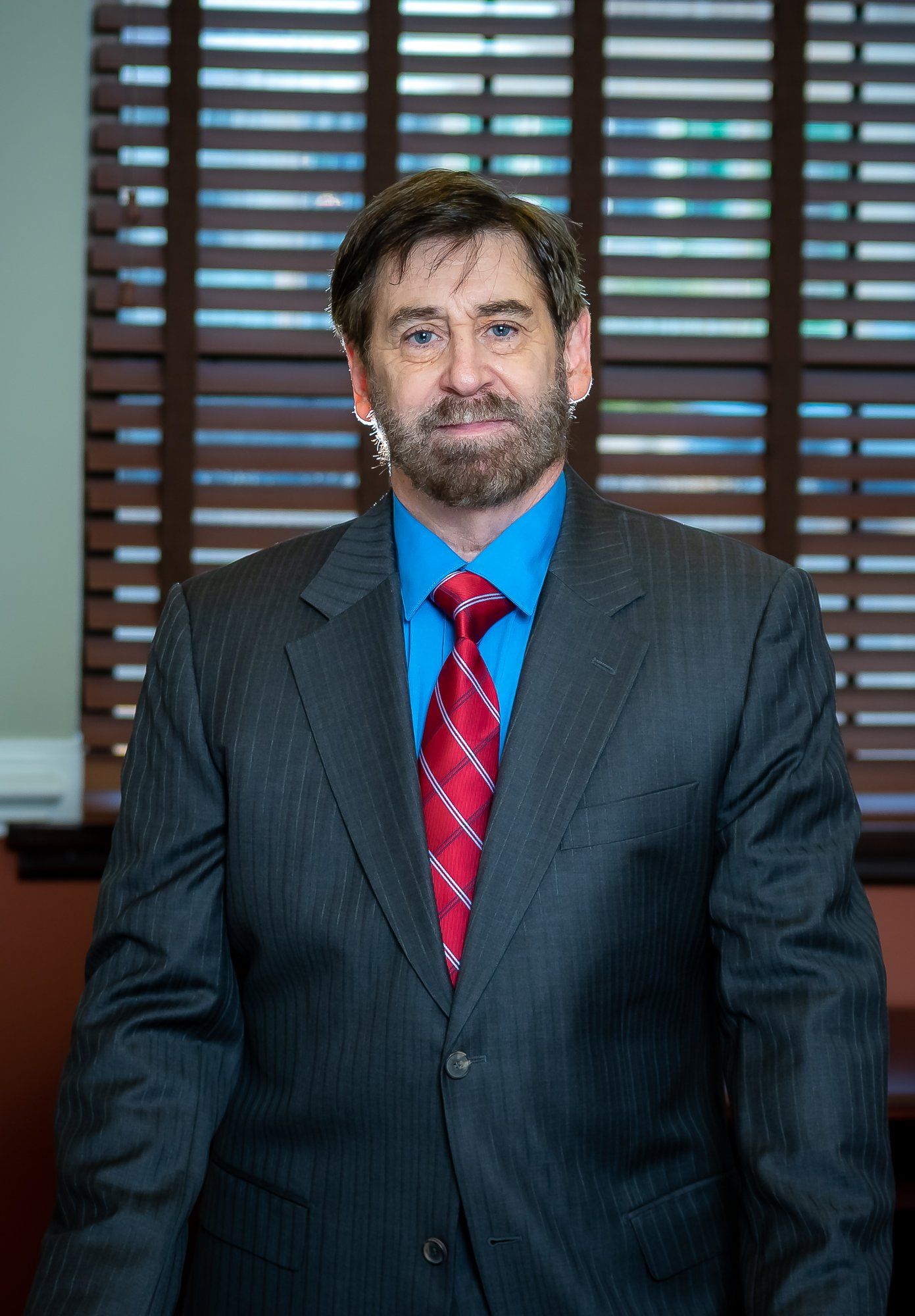 A man in a suit and tie is standing in front of a window.