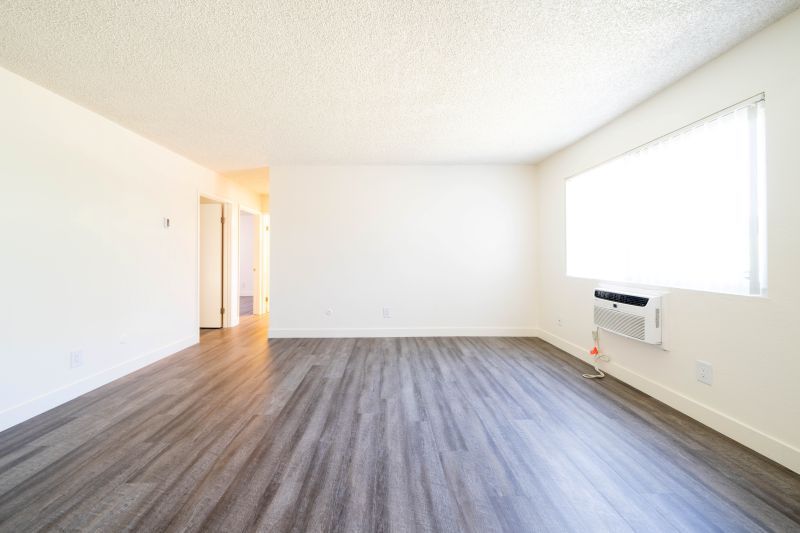 Empty bright living room with wood-look flooring and a large window near a wall heater