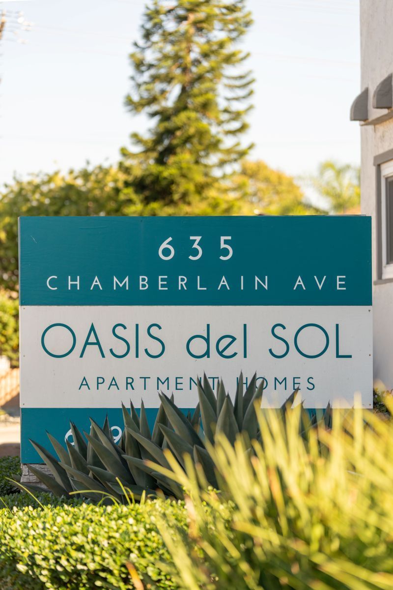 Sign for Oasis del Sol Apartments at 635 Chamberlain Ave, with greenery in front.