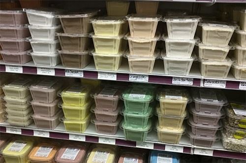 Shelves in a grocery store stocked with rows of various colors of pre-packaged food containers.