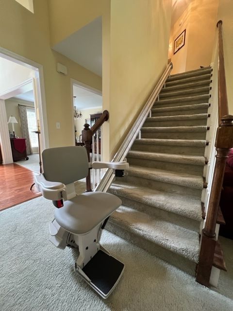 A stair lift is sitting in front of a set of stairs.